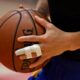 A close-up of a basketball player's hand with one finger buddy-taped to the next for support after an injury