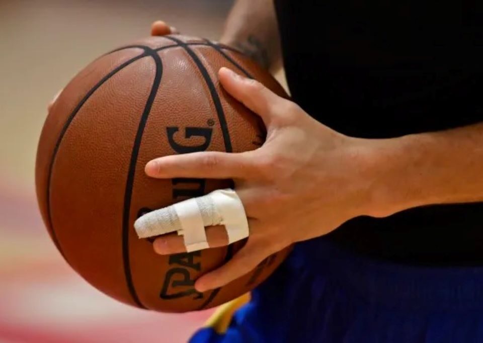 A close-up of a basketball player's hand with one finger buddy-taped to the next for support after an injury