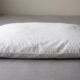 Person fluffing a bedroom pillow by hand