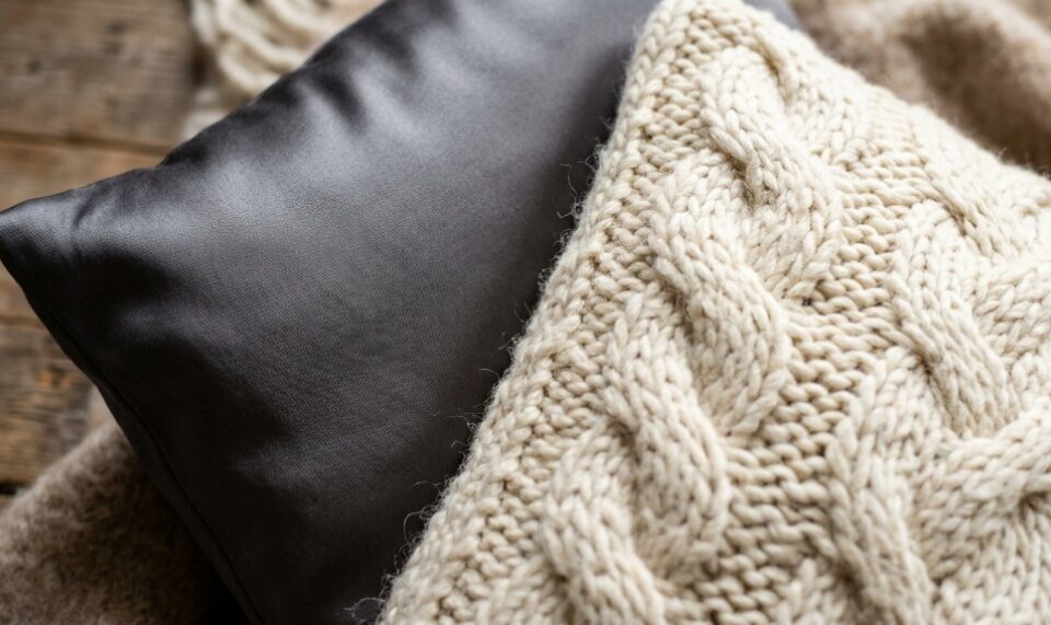 Styled bed with layered velvet, linen, and knit pillows.